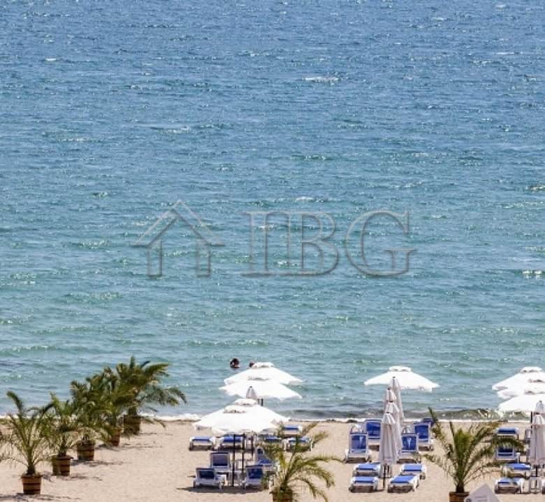 Beautiful seaside scene with clear waters, sandy beach, and sun loungers under umbrellas.