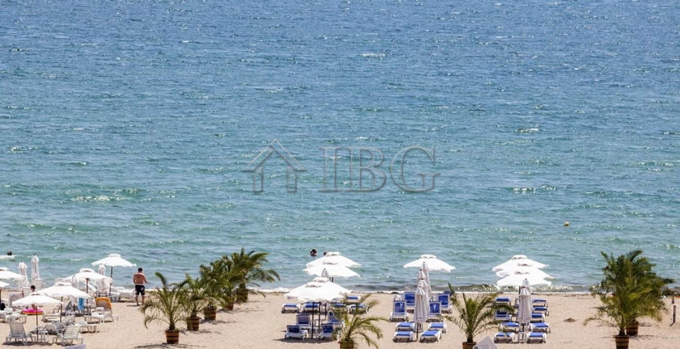 Beautiful seaside scene with clear waters, sandy beach, and sun loungers under umbrellas.