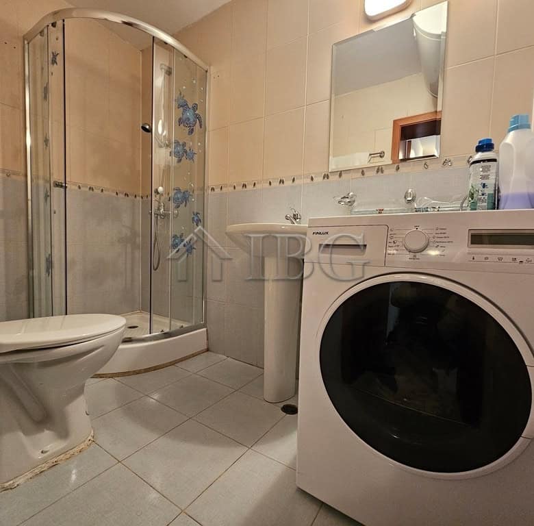 Bright bathroom with shower, washing machine, and essentials in Sveti Vlas complex.