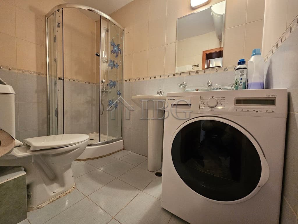 Bright bathroom with shower, washing machine, and essentials in Sveti Vlas complex.