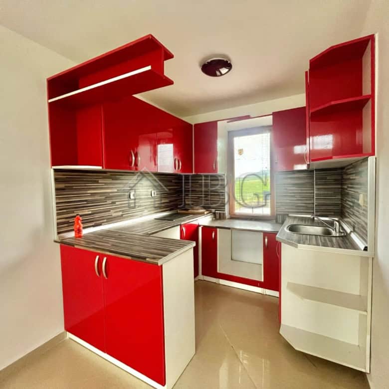 Modern red kitchen with ample storage and stainless steel appliances in Aleksandrovo, Burgas.