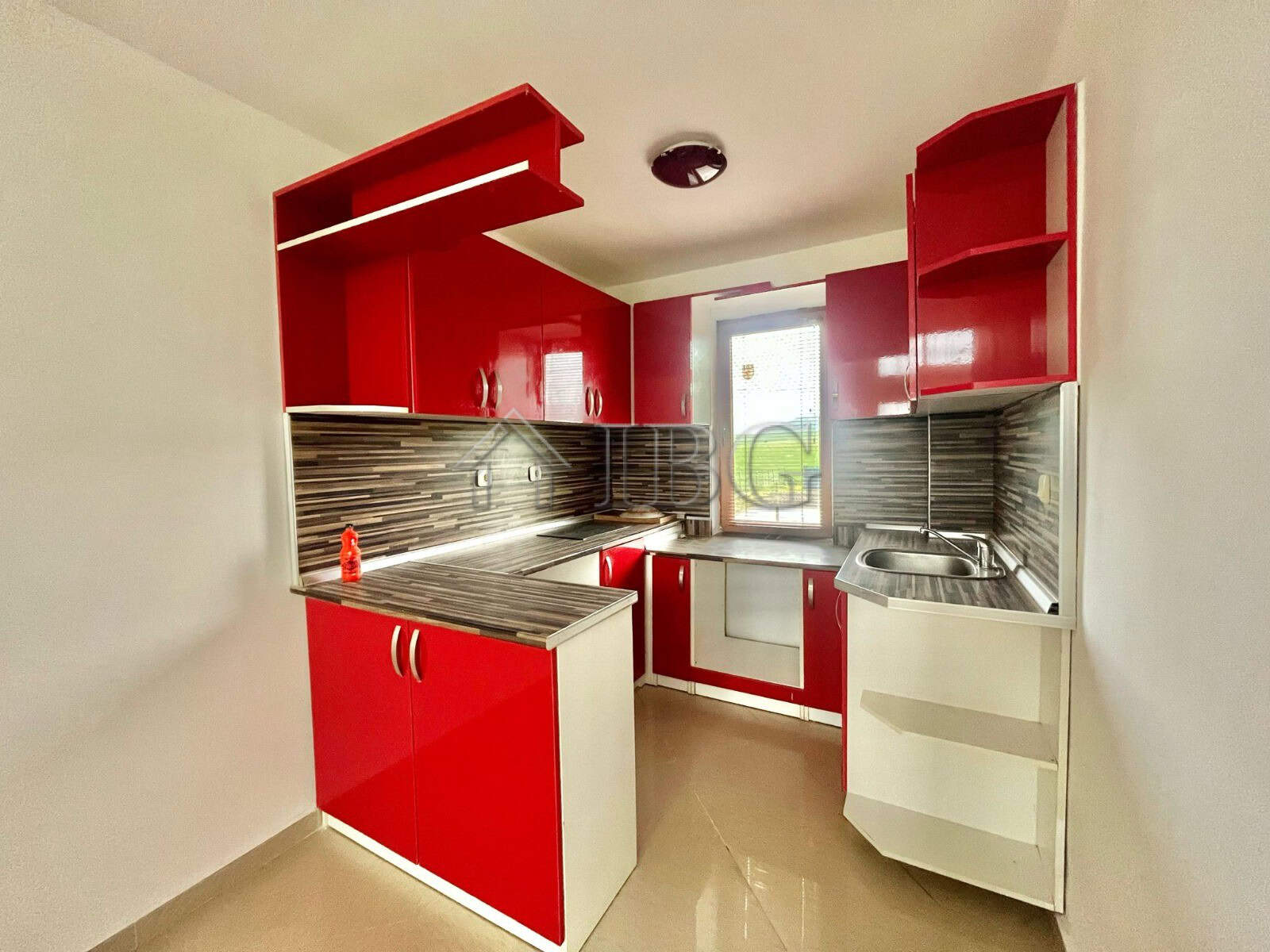 Modern red kitchen with ample storage and stainless steel appliances in Aleksandrovo, Burgas.