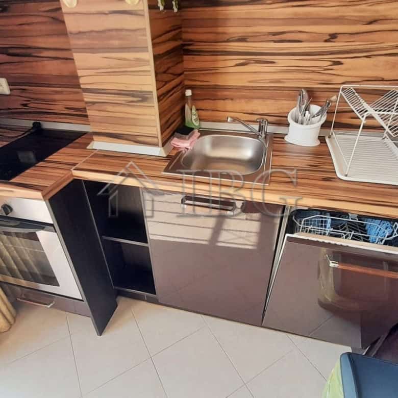 Kitchen with balcony access, featuring wooden cabinets, sink, stove, and compact appliances.