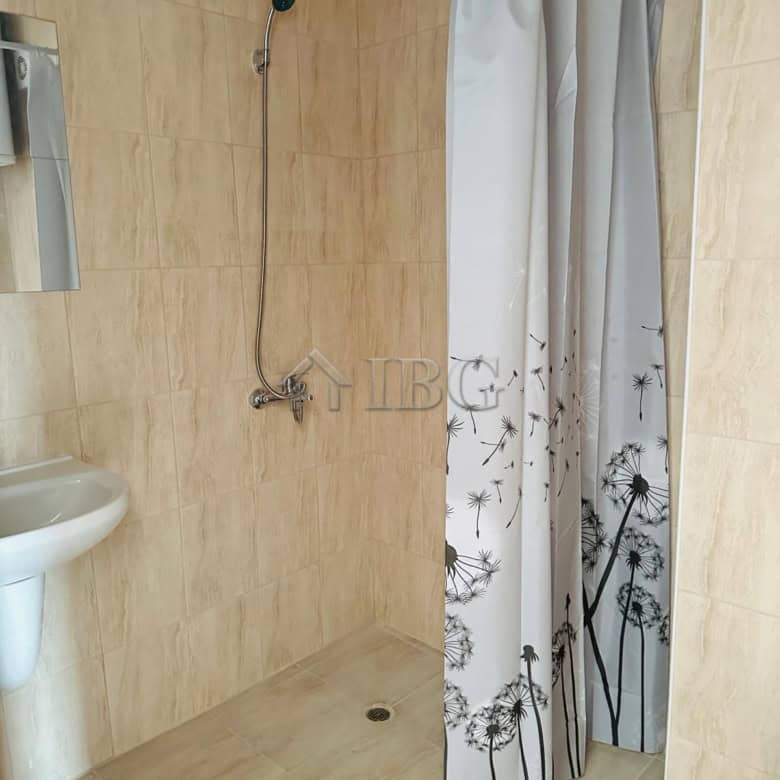 Bathroom with shower and curtain in sunny apartment.