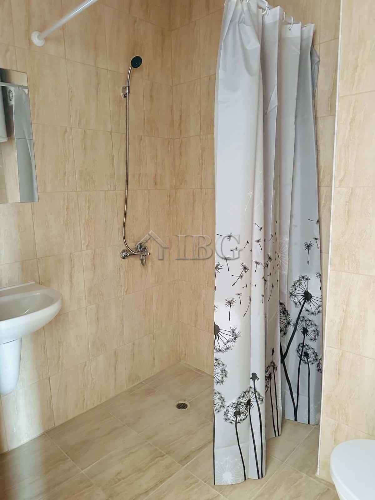 Bathroom with shower and curtain in sunny apartment.