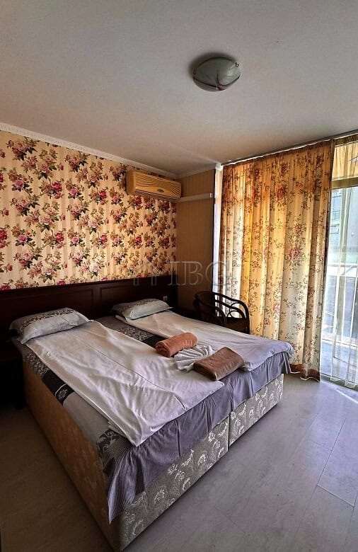 Comfortable bedroom with balcony, floral wallpaper, and partial sea view in Sunny Beach.