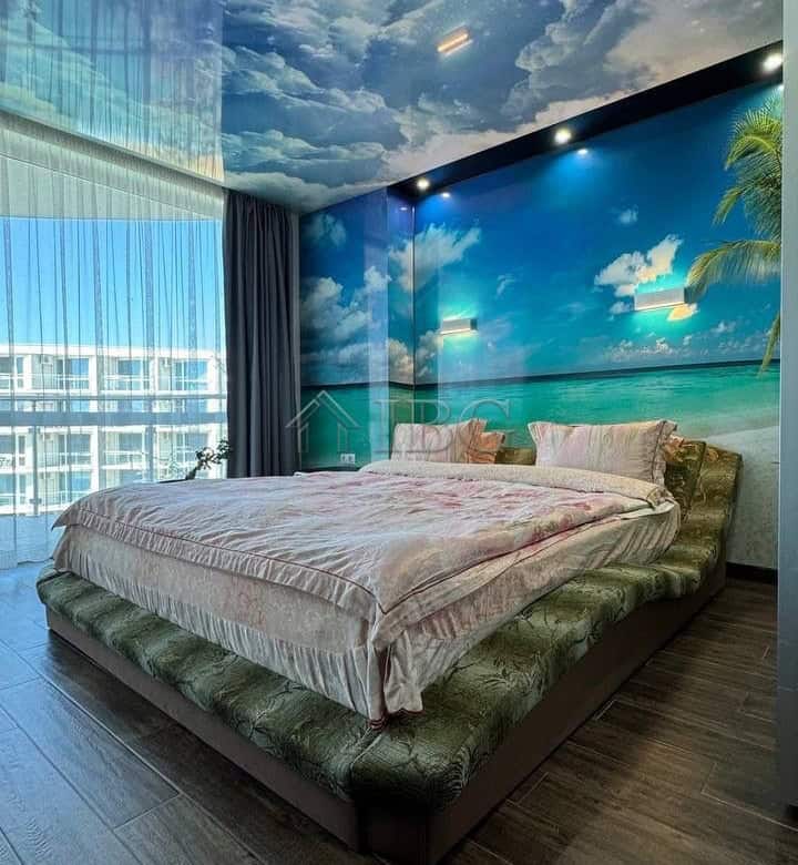 Bedroom with ocean, sky, and starry ceiling mural.