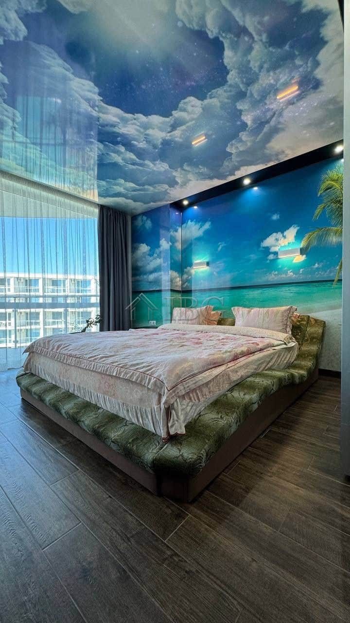 Bedroom with ocean, sky, and starry ceiling mural.