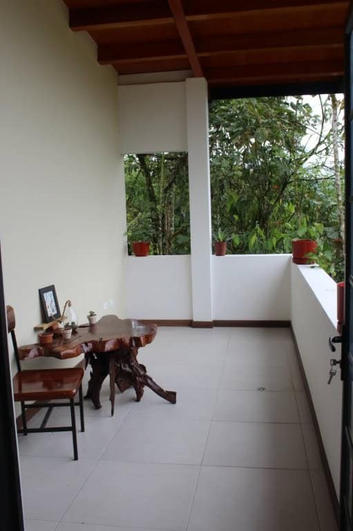 Spacious balcony of a 5-bedroom house in Portal de Mindo, Ecuador, with lush greenery and outdoor se.
