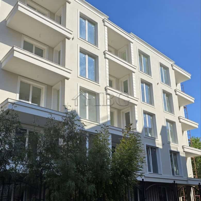 Contemporary white apartment building with multiple balconies in sunny weather.