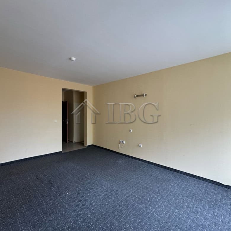 Interior view of a hotel section with beige walls and dark carpet flooring, ready for renovation or.