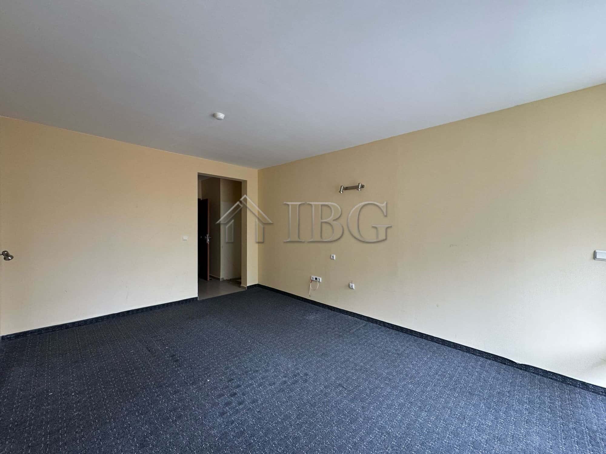 Interior view of a hotel section with beige walls and dark carpet flooring, ready for renovation or.