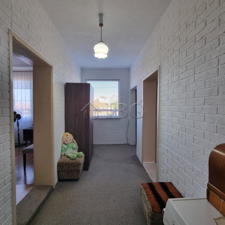 Cozy interior hallway with white brick walls, a window, and simple furniture in Vinarsko Village, Bu.
