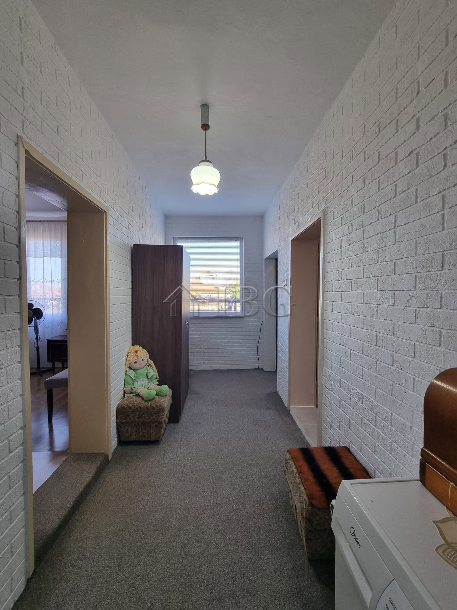 Cozy interior hallway with white brick walls, a window, and simple furniture in Vinarsko Village, Bu.