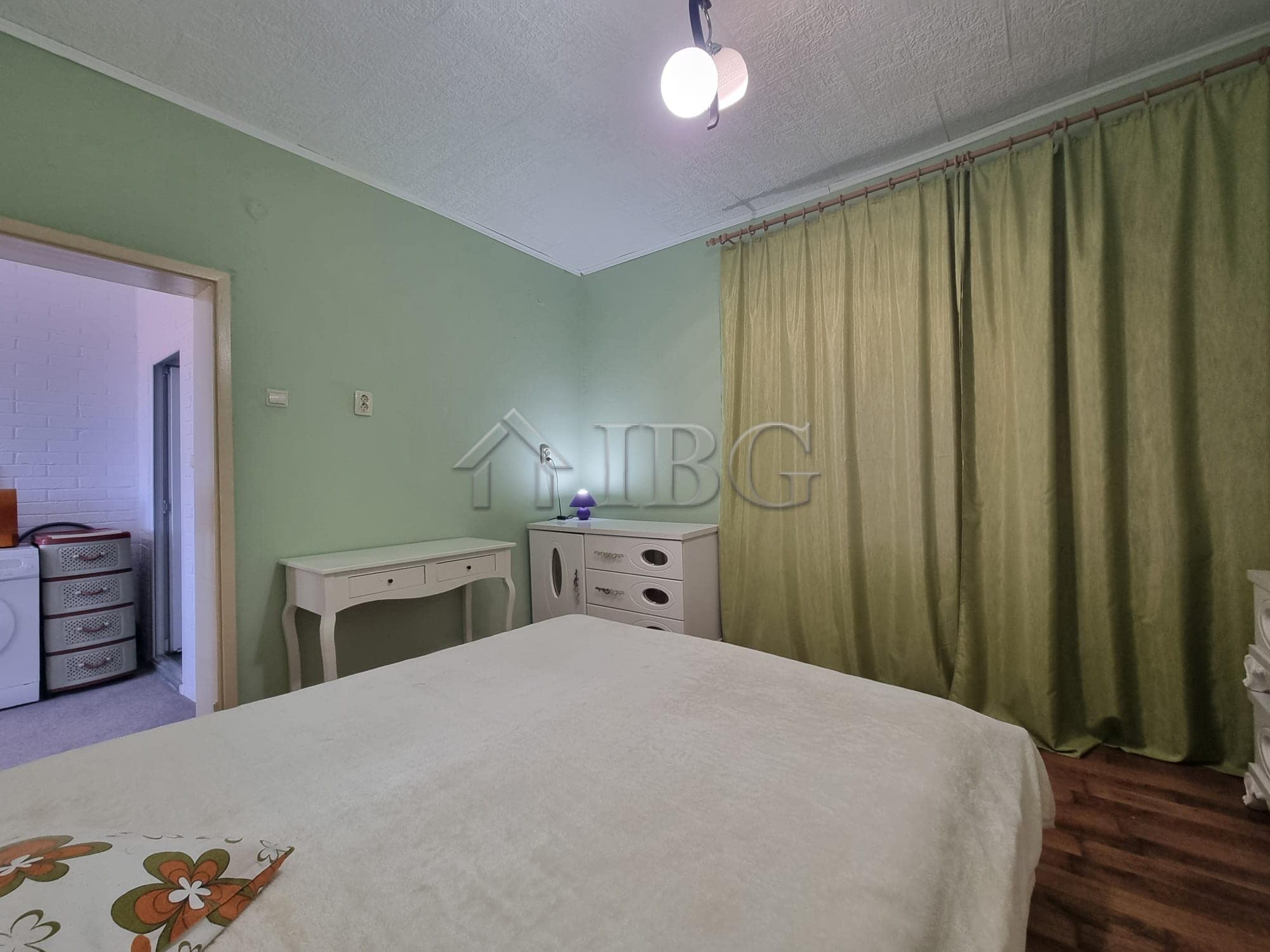 Cozy bedroom in Vinarsko Village with green walls and large curtains, ideal for a peaceful countrysi.