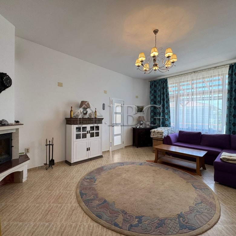 Bright living room with large window, purple sofa, and elegant chandelier in Kosharitsa home.