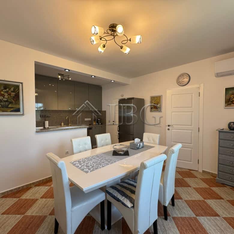 Spacious dining area with modern decor, white furniture, and a stylish chandelier, perfect for famil.