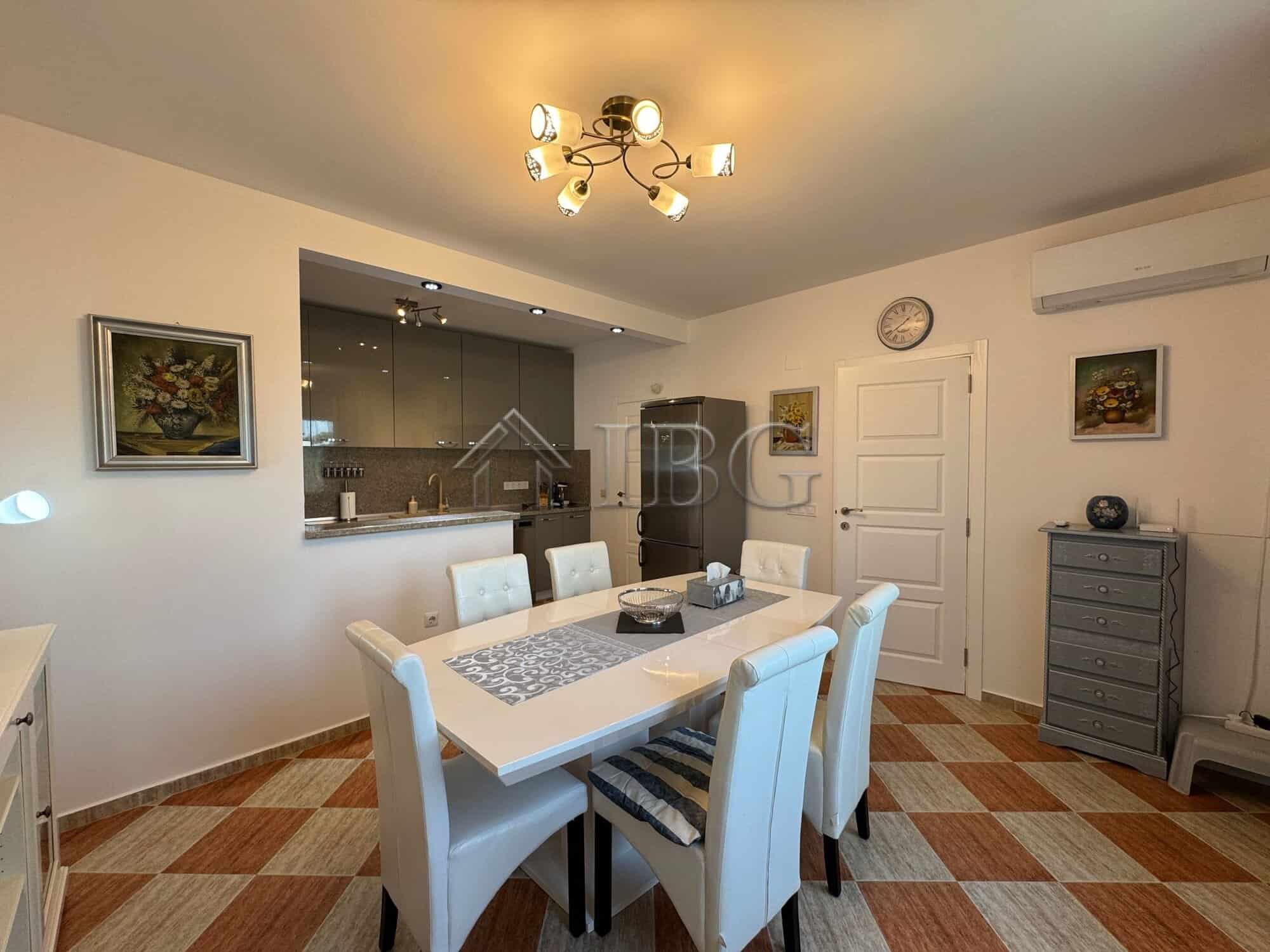Spacious dining area with modern decor, white furniture, and a stylish chandelier, perfect for famil.