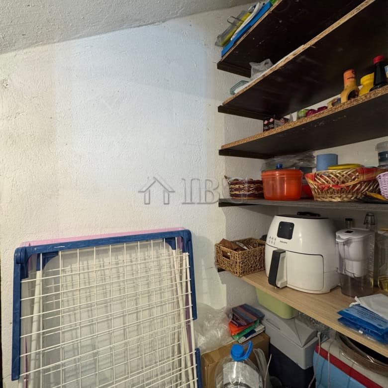 Interior view of a small kitchen storage with shelves, appliances, and kitchenware in Kosharitsa hom.