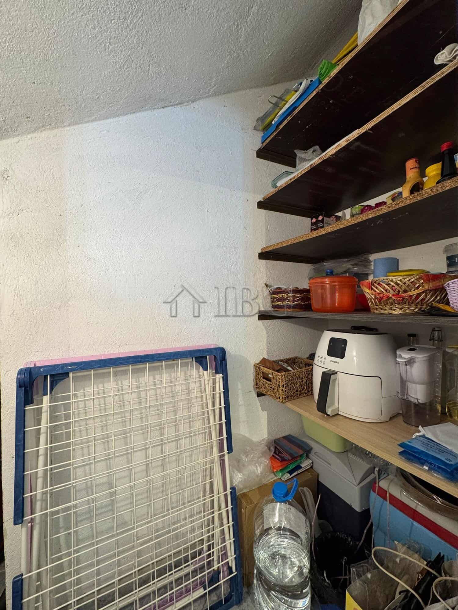 Interior view of a small kitchen storage with shelves, appliances, and kitchenware in Kosharitsa hom.