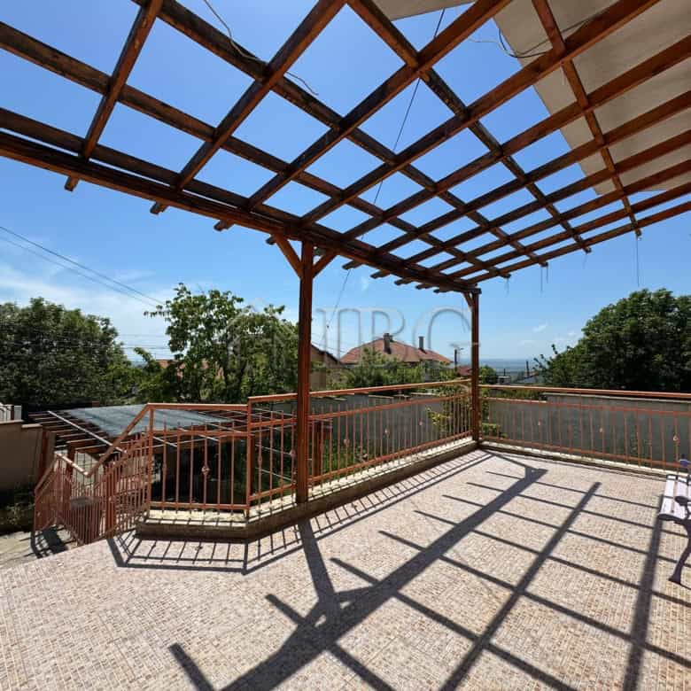 Large outdoor balcony with wooden pergola overlooking lush greenery and distant sea views. Perfect f.