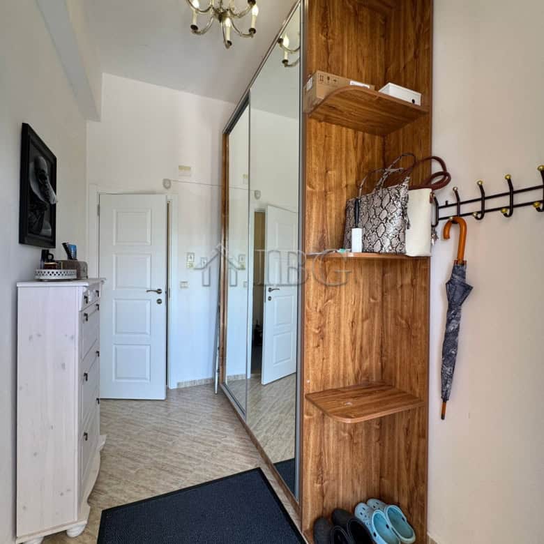 Modern hallway with wooden storage unit and mirror closet.