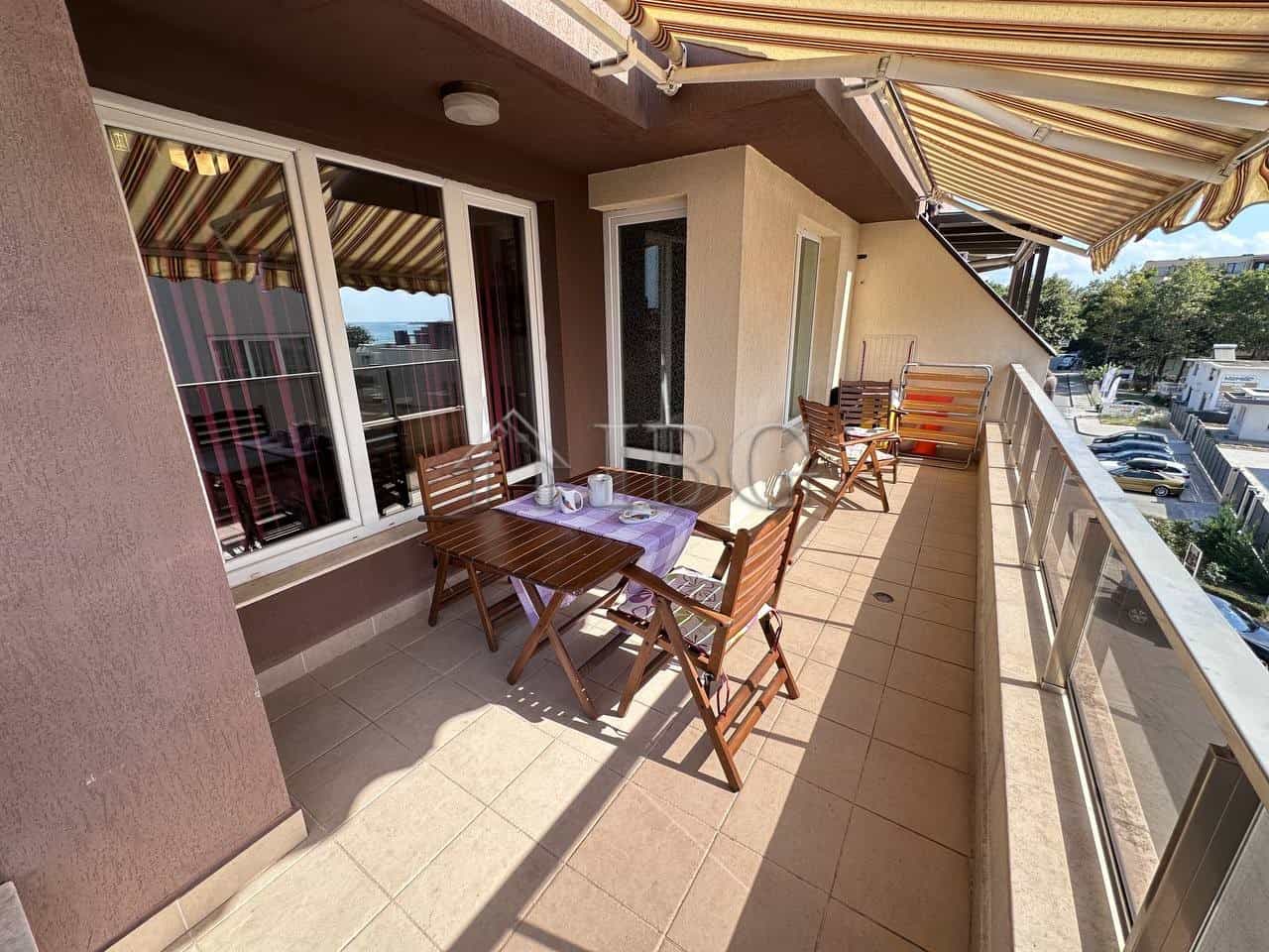 Balcony of a 1-bedroom apartment in Ravda with outdoor dining area and partial sea views.