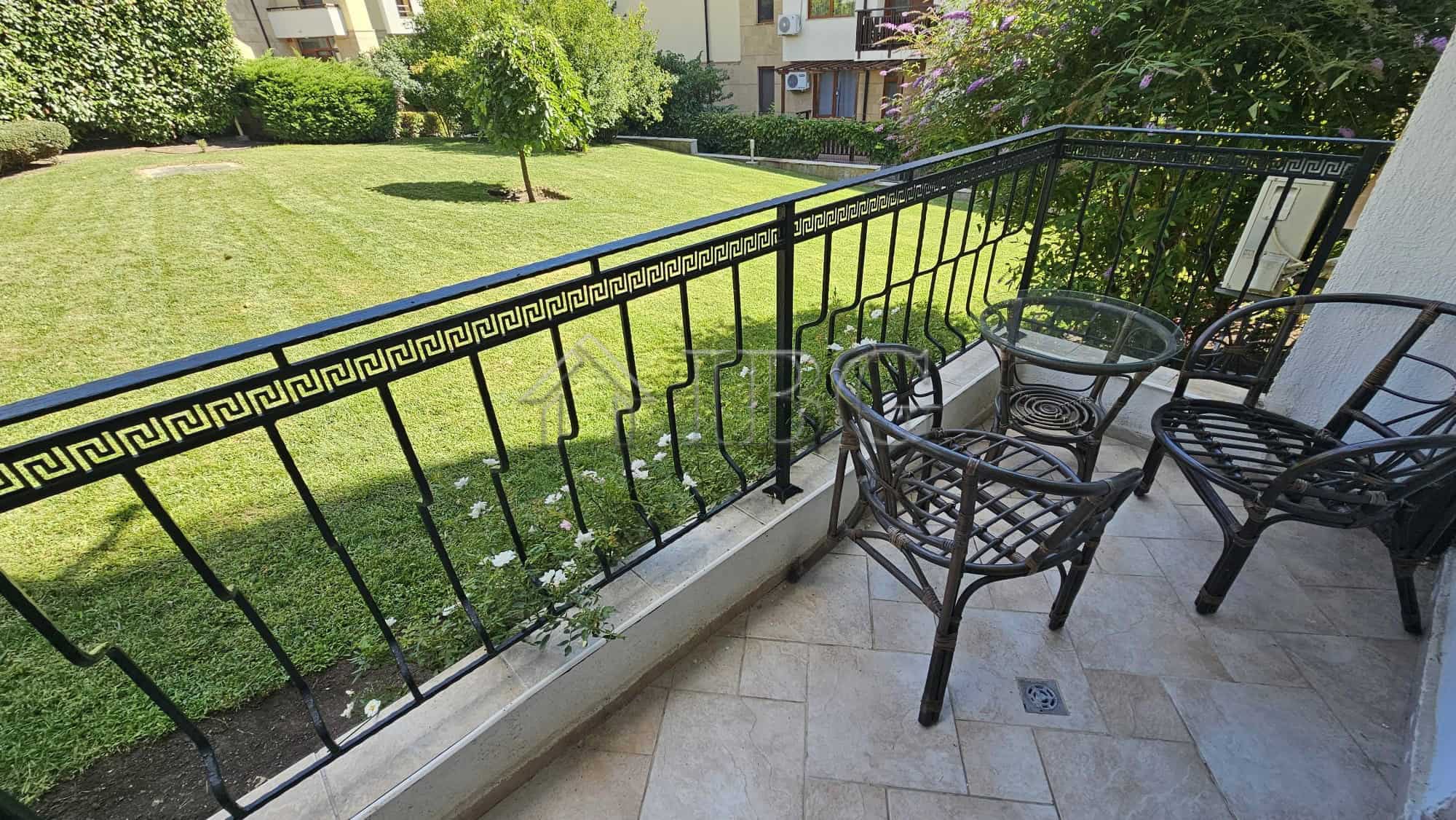 Balcony with outdoor seating overlooking a lush park in Sveti Vlas.