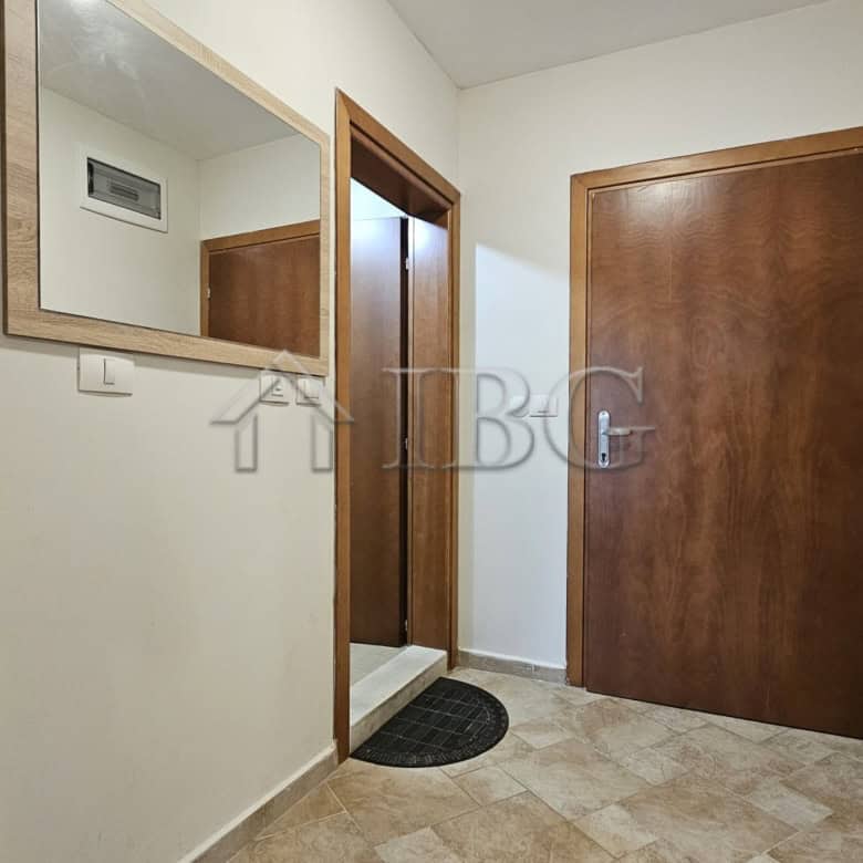 Entrance hall of a 1-bedroom apartment with wooden doors and a large mirror.