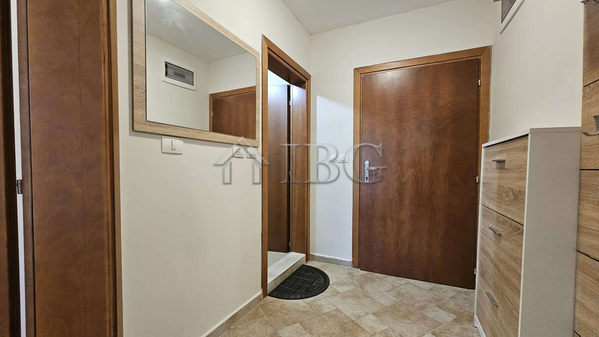 Entrance hall of a 1-bedroom apartment with wooden doors and a large mirror.