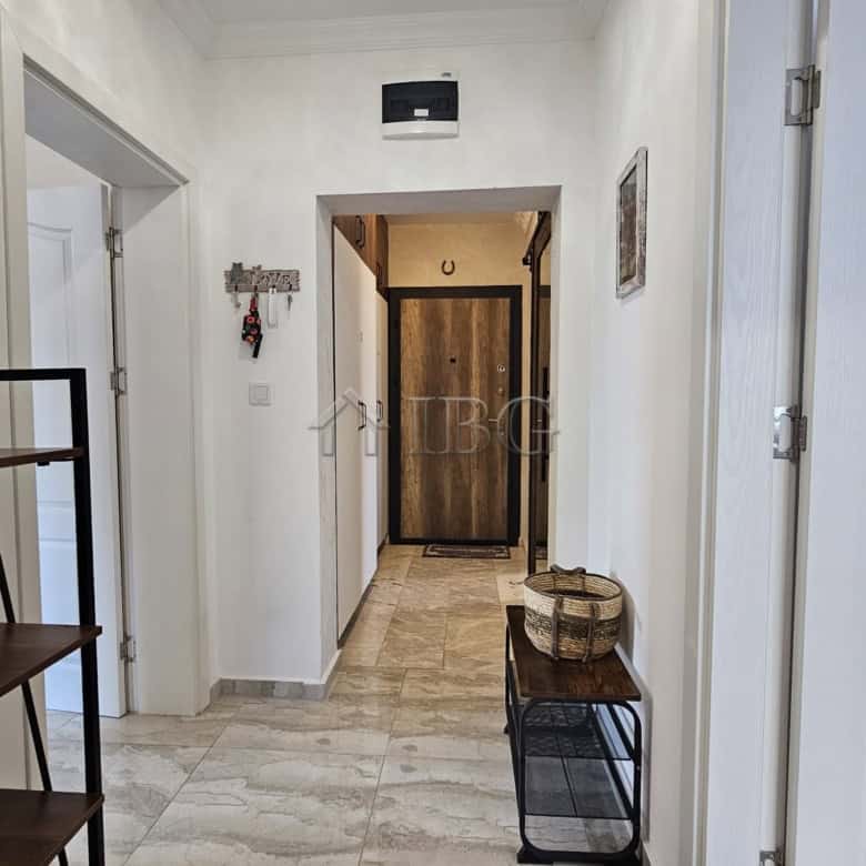 Interior view of a bright, spacious apartment hallway with white walls and marble flooring.