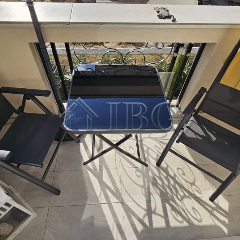 Balcony with two chairs, a small table, and a view of Sunny Beach from a spacious apartment.