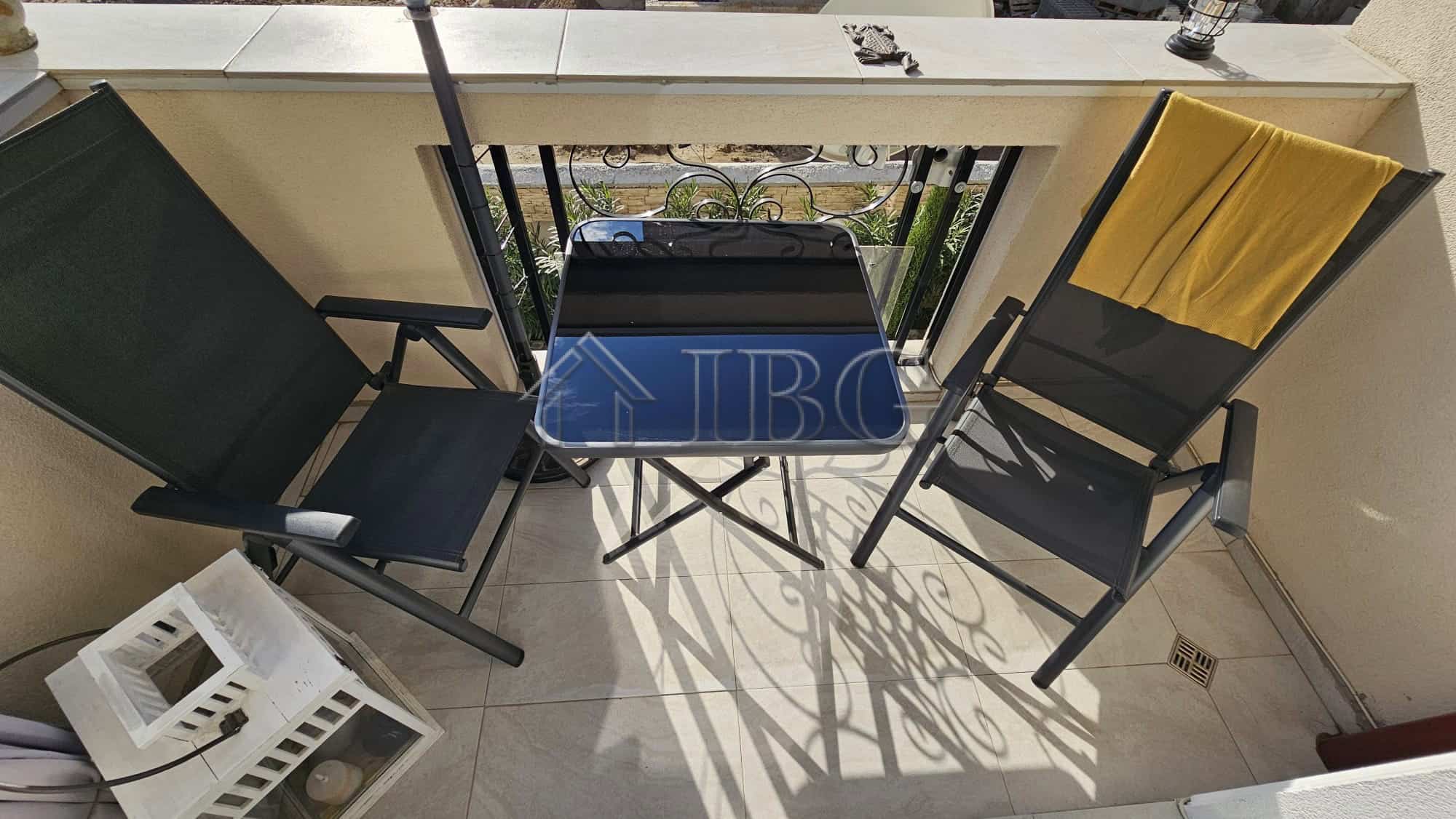 Balcony with two chairs, a small table, and a view of Sunny Beach from a spacious apartment.
