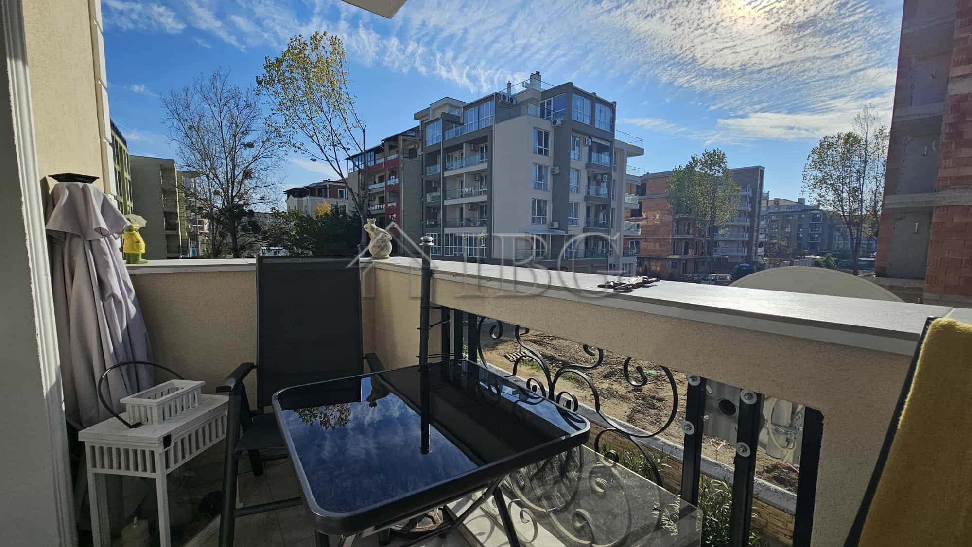 Balcony view of a spacious apartment in Magnolia 6, Sunny Beach, with outdoor seating and cityscape.