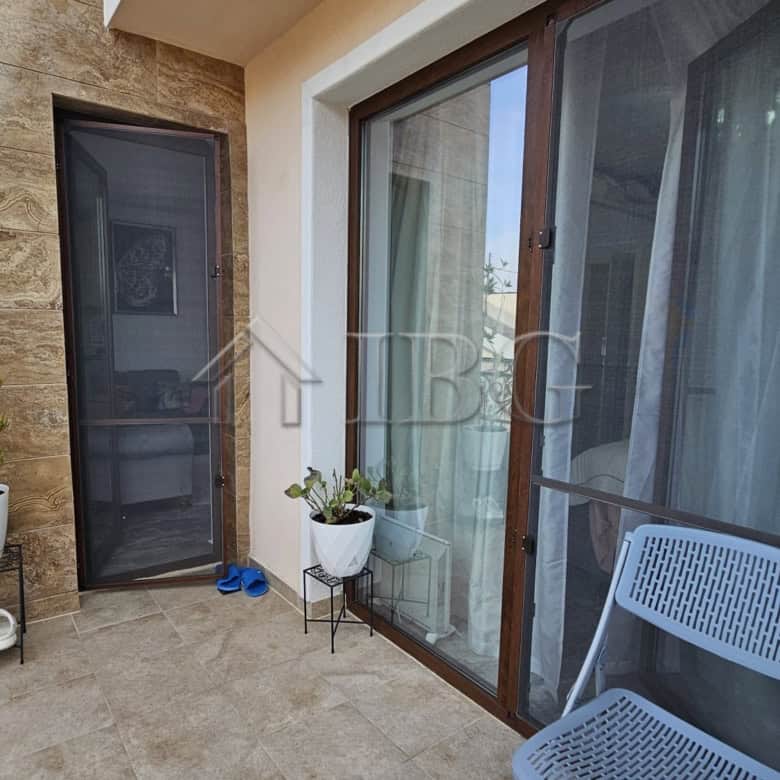 Balcony of a one-bedroom apartment in Valencia Gardens, Nessebar, featuring outdoor seating and pott.