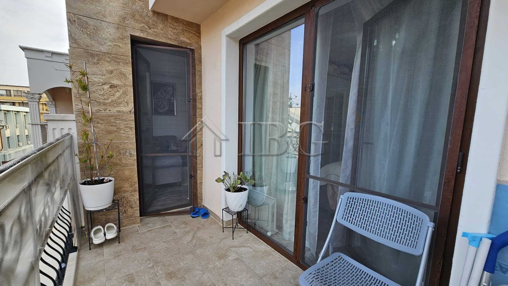 Balcony of a one-bedroom apartment in Valencia Gardens, Nessebar, featuring outdoor seating and pott.