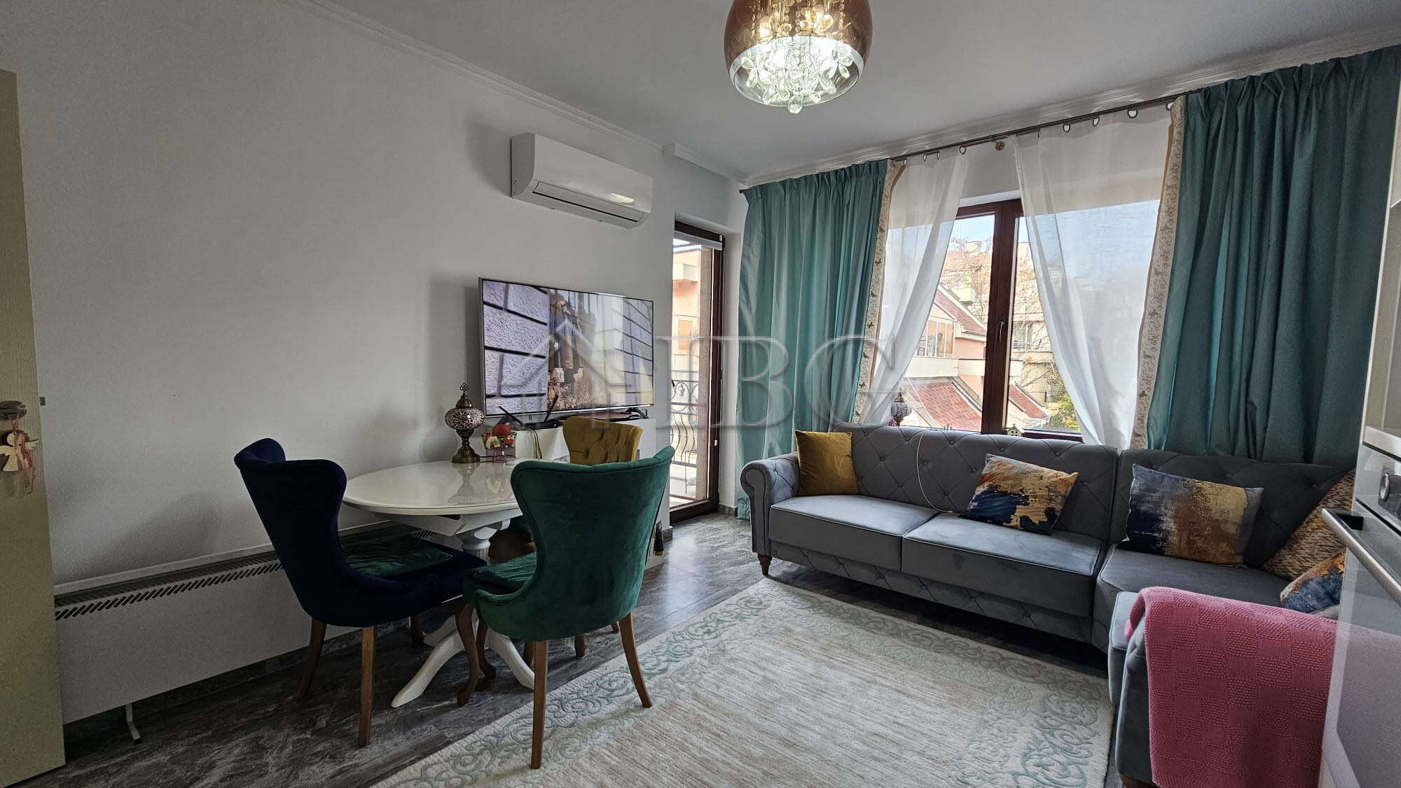 Bright living space with large windows, stylish furniture, and cozy decor.