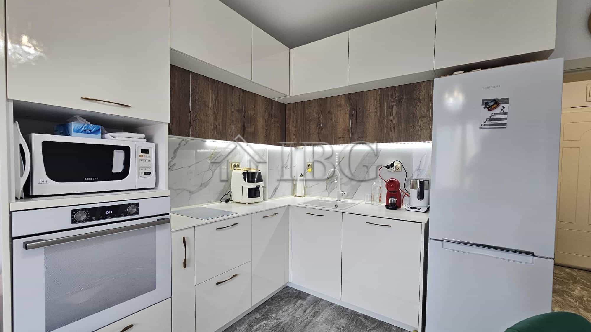 Contemporary kitchen with white cabinets, marble backsplash, and modern appliances in Valencia Garde.