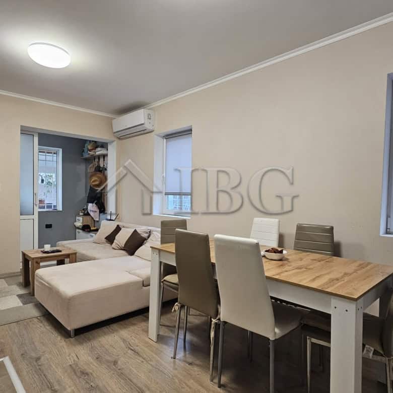 Bright living space featuring a comfortable sofa, dining table, and large windows.