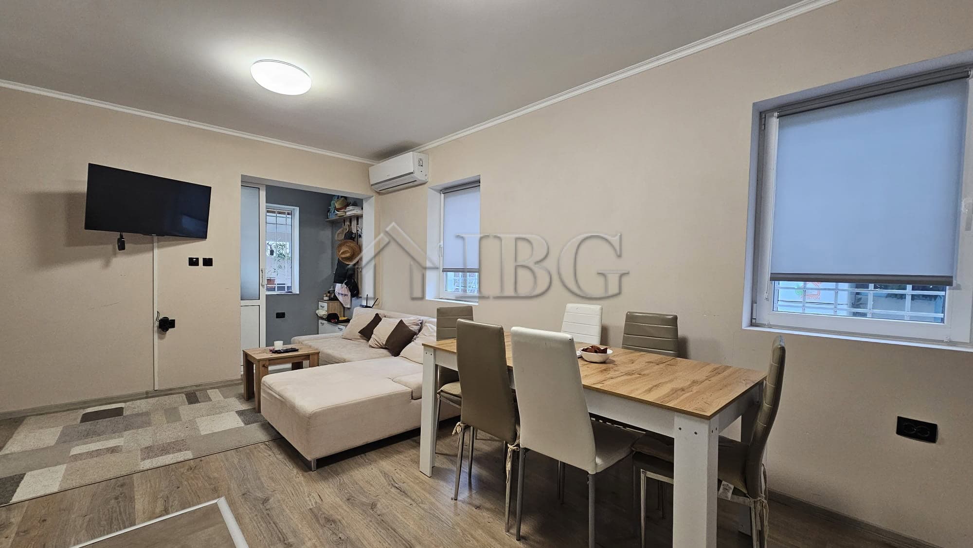 Bright living space featuring a comfortable sofa, dining table, and large windows.