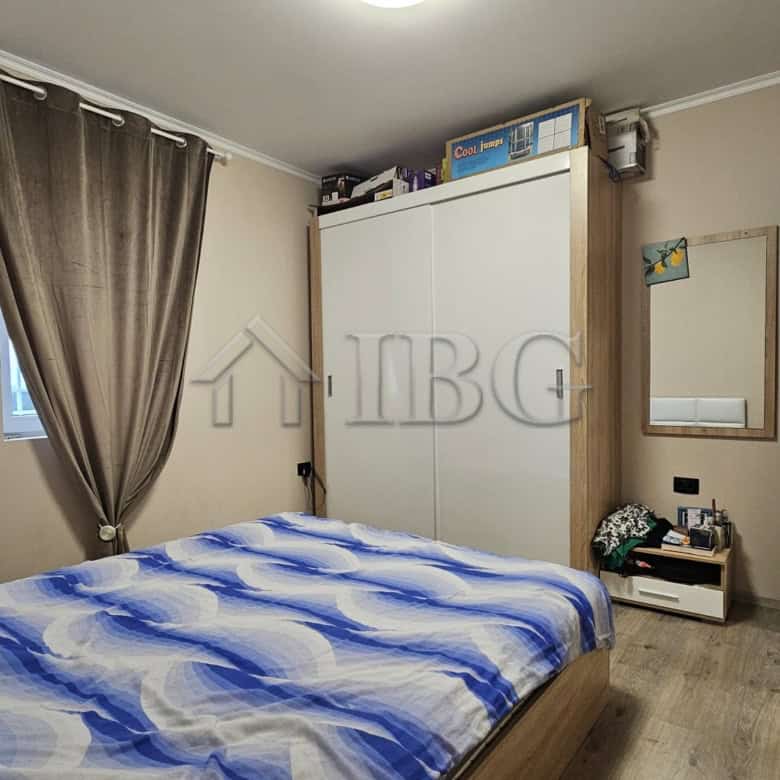 Interior view of a bedroom with a bed, wardrobe, and window with curtains.