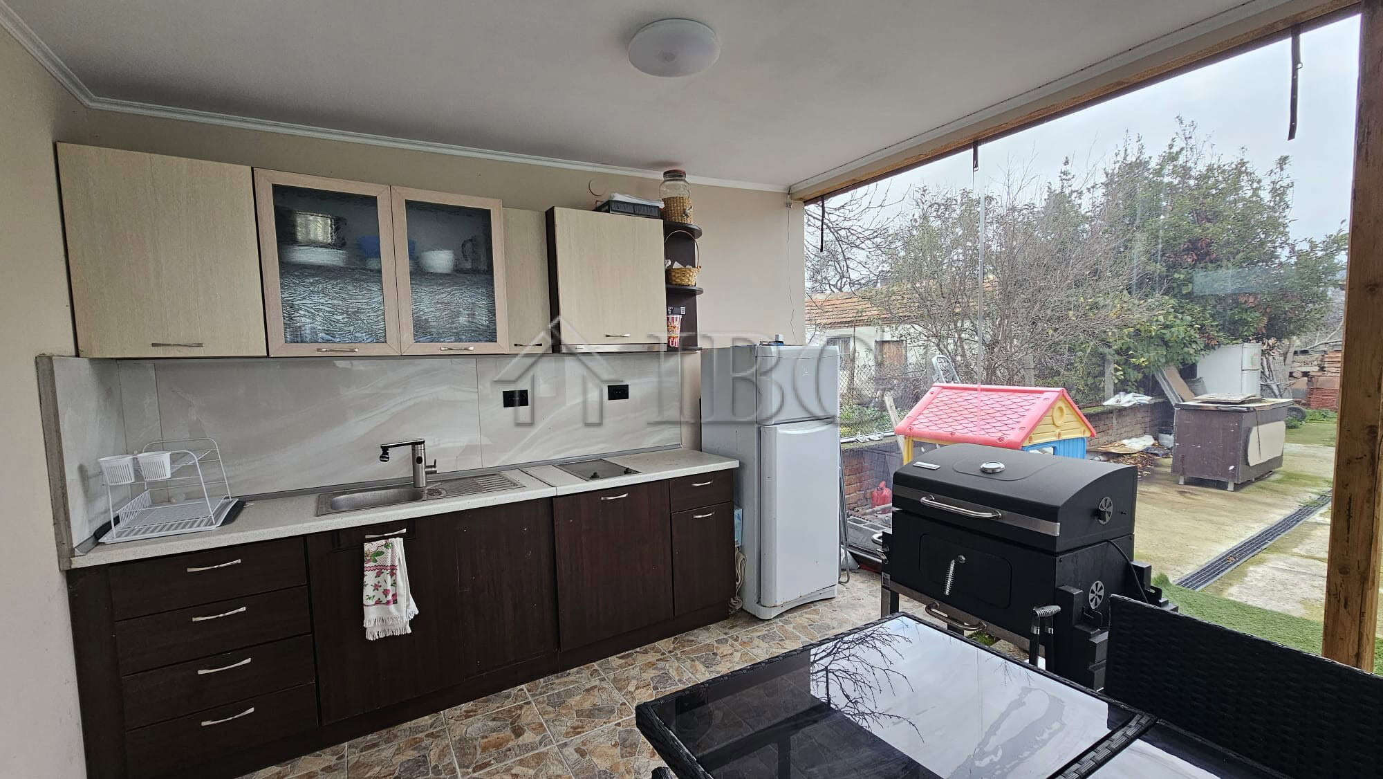 Bright kitchen with garden view and outdoor barbecue area for relaxing meals.