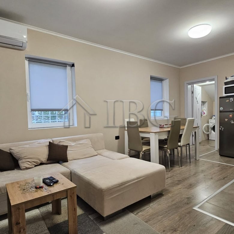 Spacious living room featuring a comfortable sofa, dining table, and open kitchen setup.