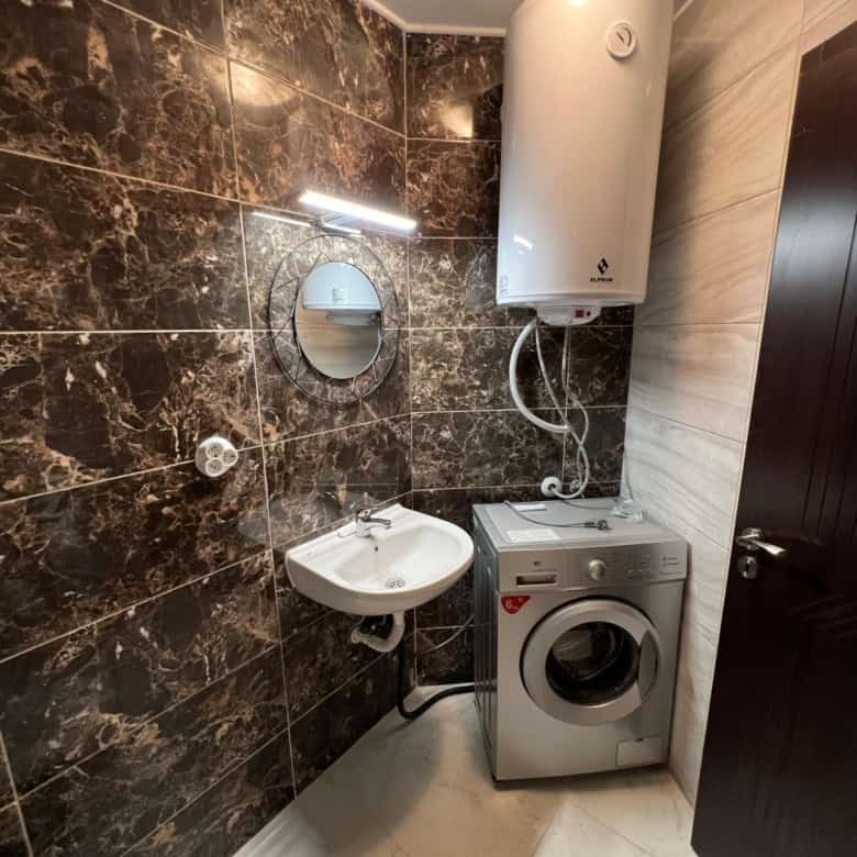Compact bathroom with washing machine, water heater, and mirror in Ipanema Beach Complex, Saint Vlas.