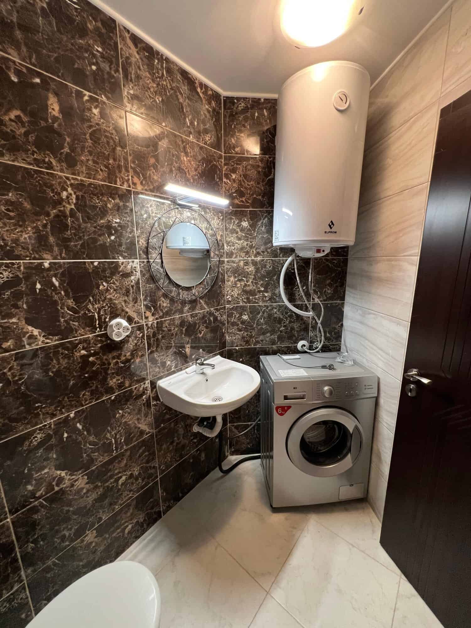 Compact bathroom with washing machine, water heater, and mirror in Ipanema Beach Complex, Saint Vlas.