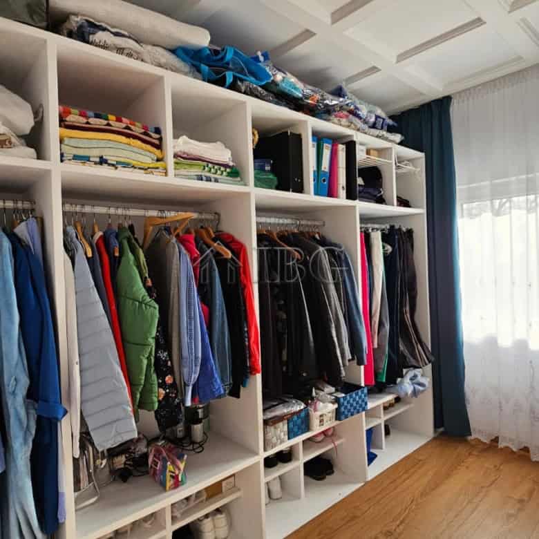 Bright walk-in closet with organized shelves and hanging space in a renovated detached house.