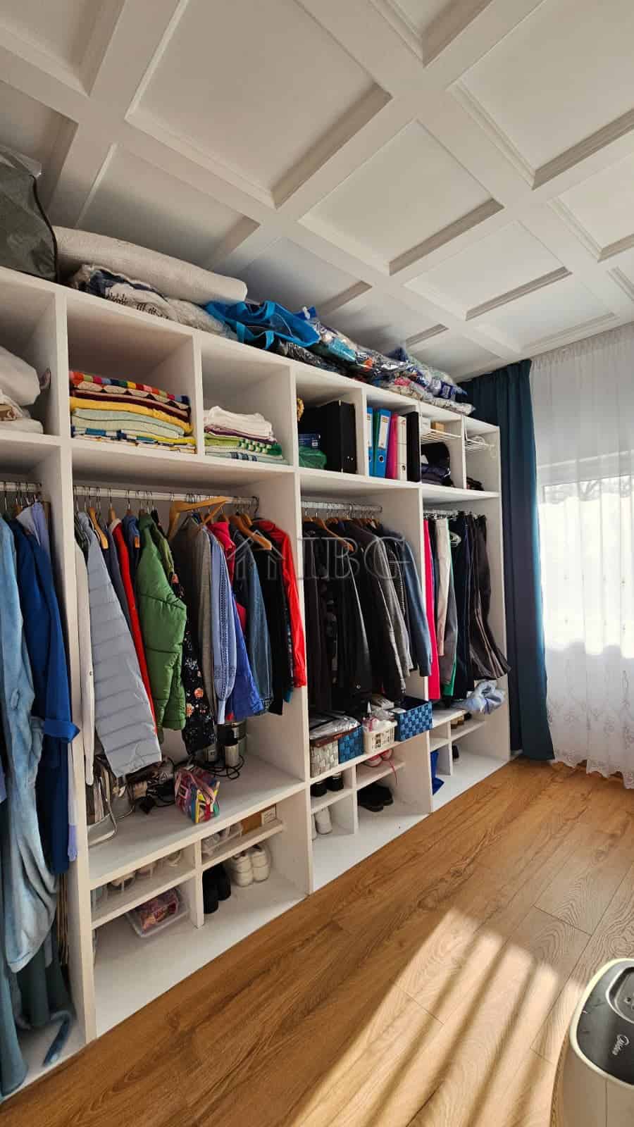 Bright walk-in closet with organized shelves and hanging space in a renovated detached house.