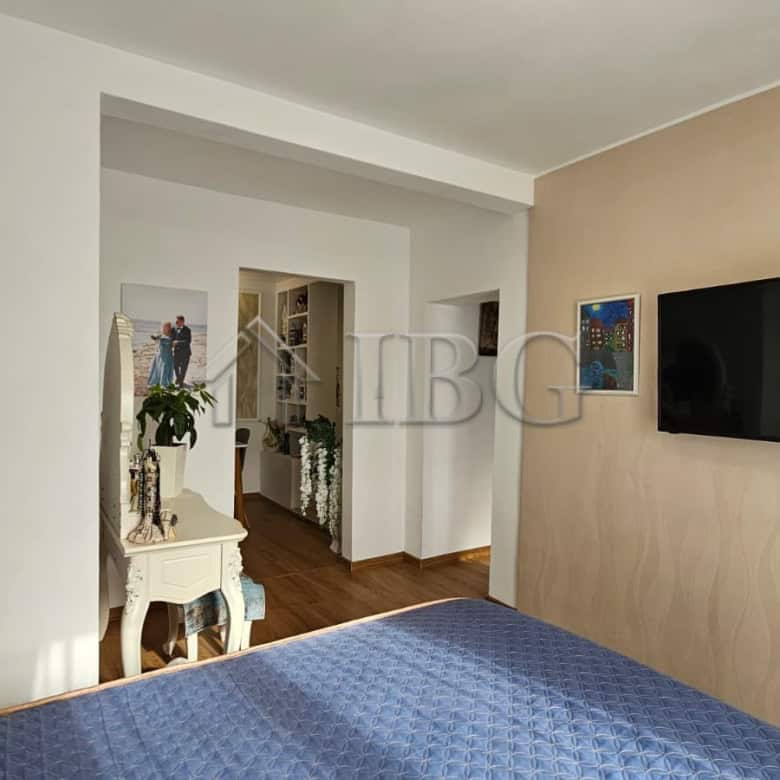 Modern bedroom with blue bedspread, wall-mounted TV, and stylish decor in Kosharitsa.