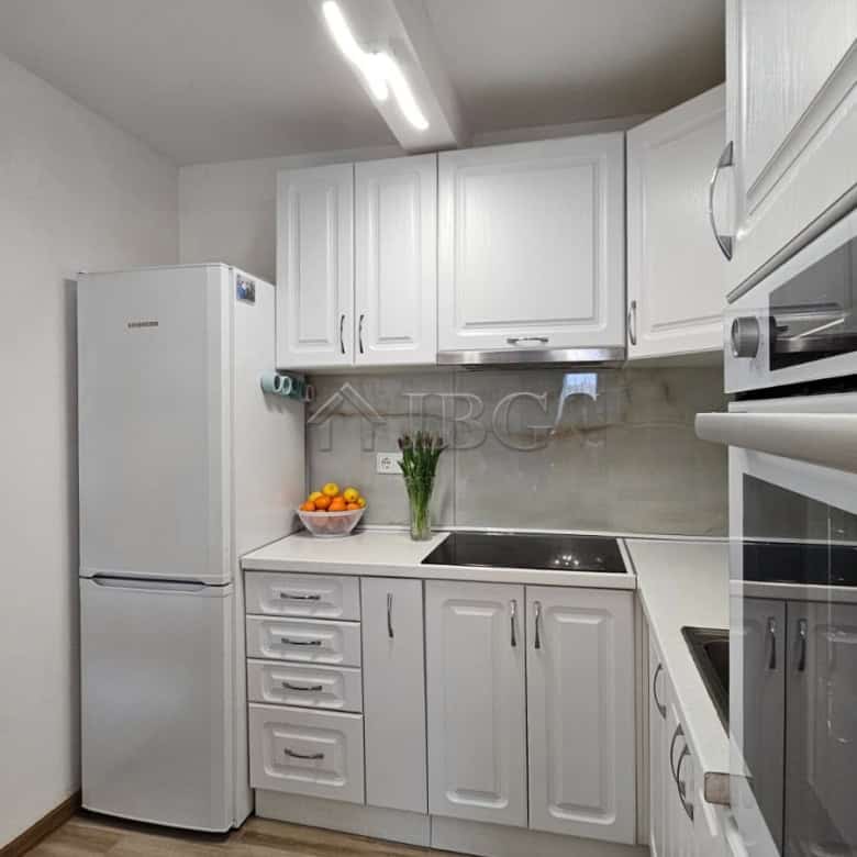 Bright modern kitchen with white cabinets, refrigerator, and built-in oven near Sunny Beach.