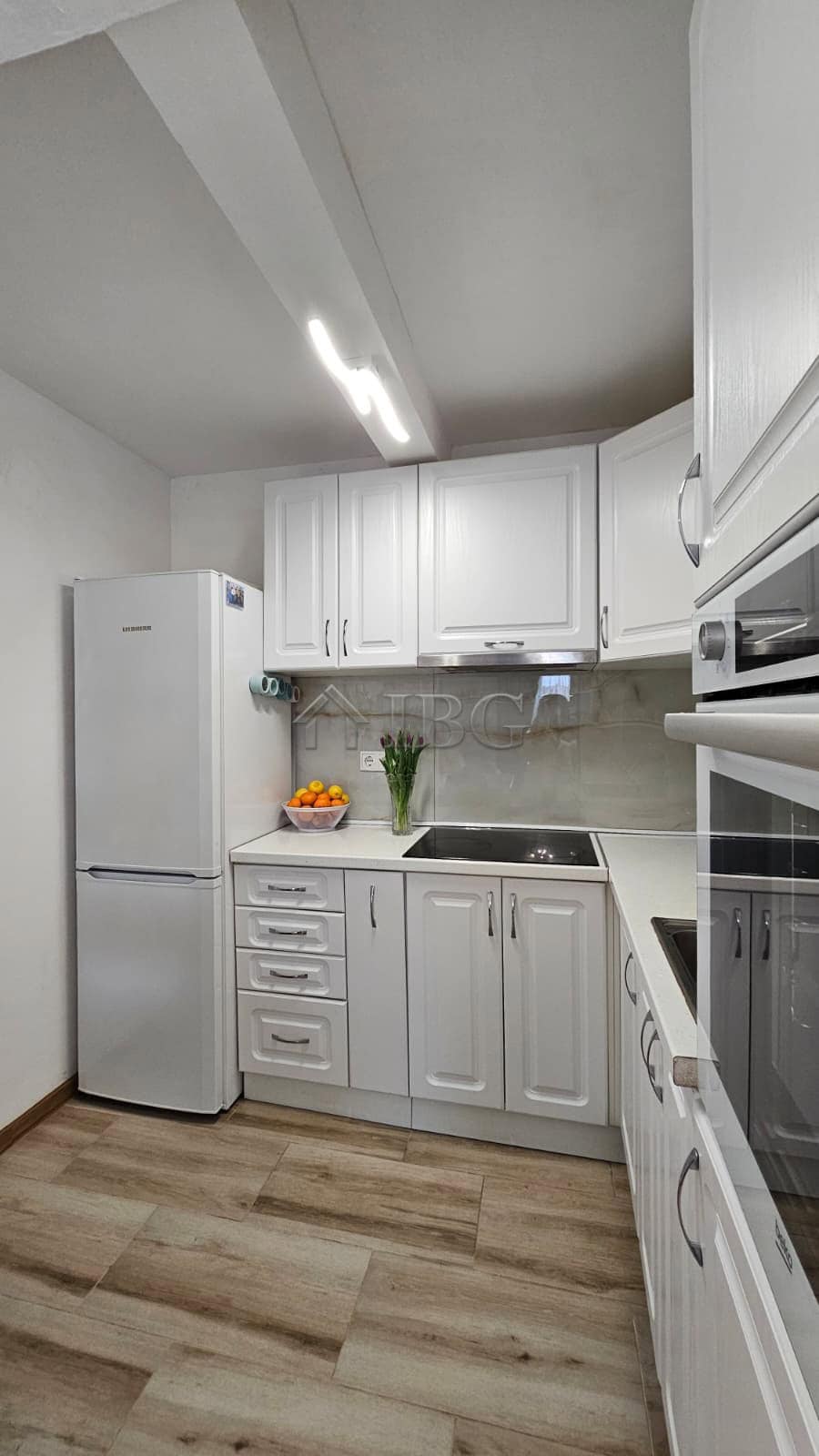 Bright modern kitchen with white cabinets, refrigerator, and built-in oven near Sunny Beach.